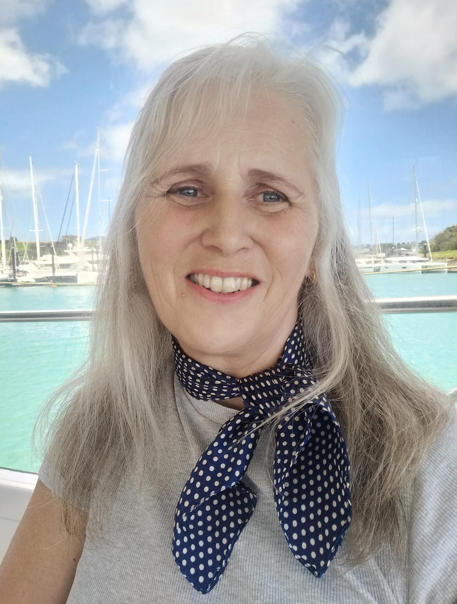 author photo sitting in front of a turquoise sea and blue sky