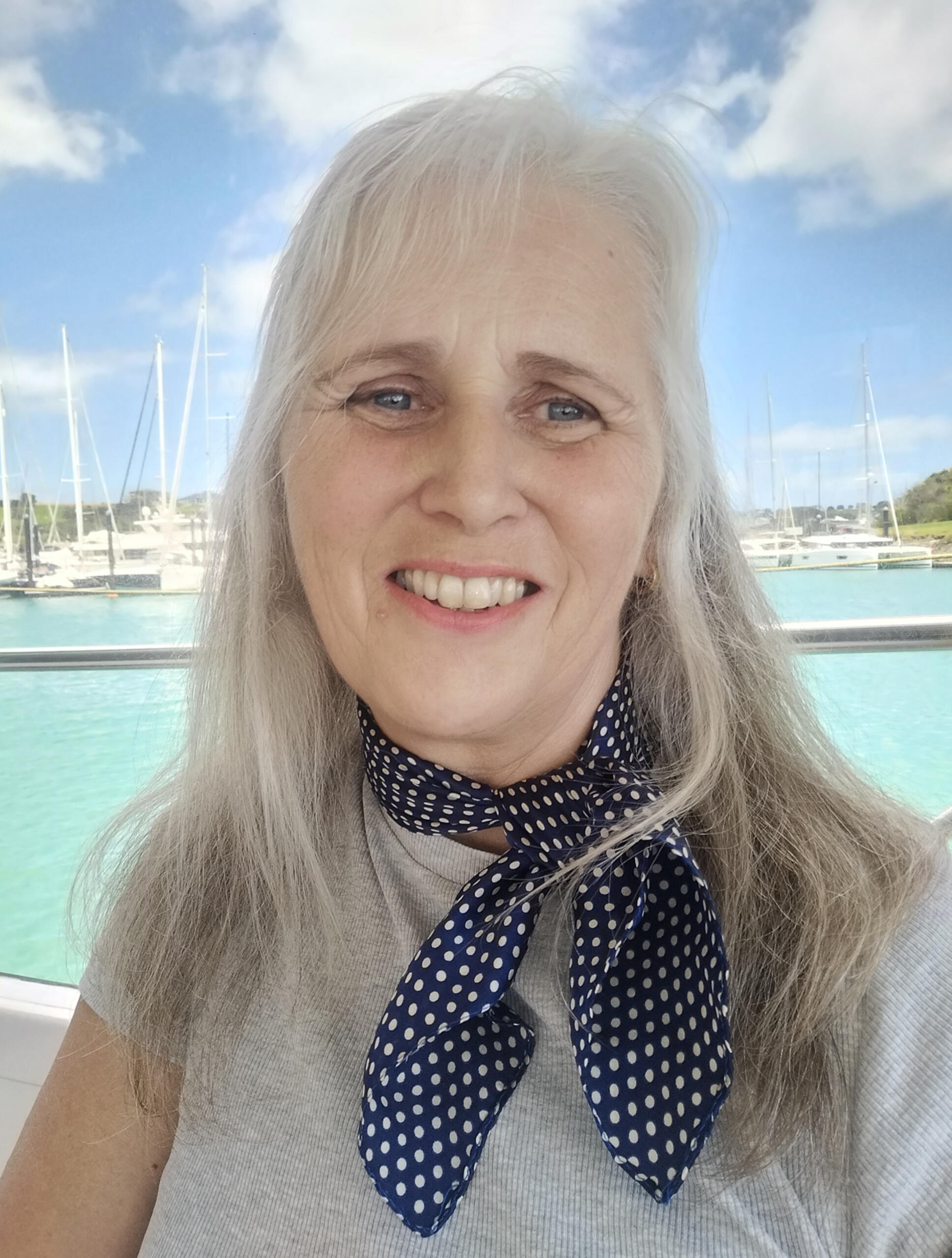 Penelope Clare author photo sitting in front of a turquoise sea and blue sky